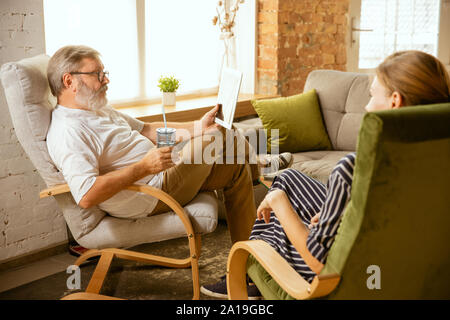 Senior man working with tablet at home - concept of home studying. Caucasian male model doing his homework with teacher while serfing in internet, watching cinema or webinar, online lessons. Stock Photo
