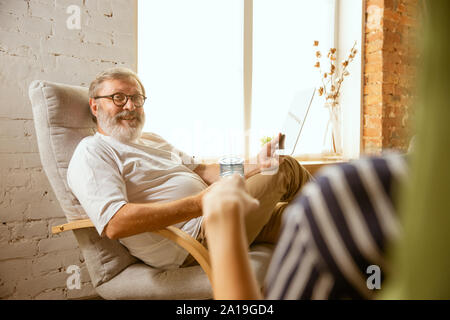 Senior man working with tablet at home - concept of home studying. Caucasian male model doing his homework with teacher while serfing in internet, watching cinema or webinar, online lessons. Stock Photo