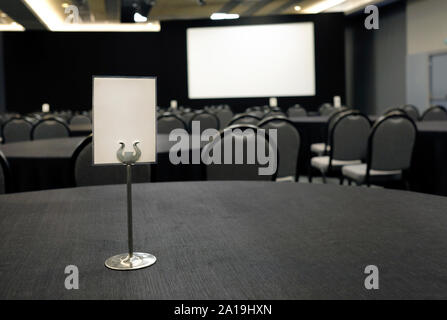 Empty sign and screen in a conference room filled with tables and chairs Stock Photo