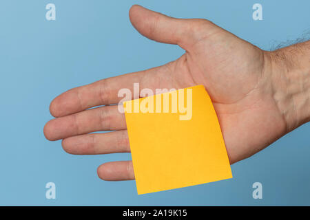 yellow adhesive sticky reminder note stuck to a hand, blank. Stock Photo