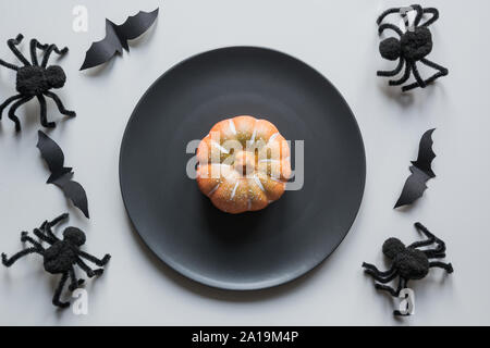 Halloween concept table setting with black spiders, bat, pumpkin on grey table .Flat lay, top view. Party accessories. Stock Photo