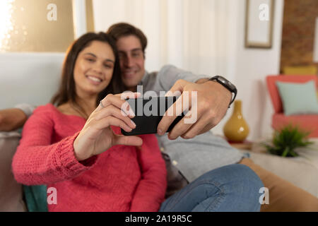 Young couple relaxing at home using a smartphone together Stock Photo