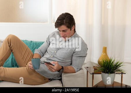 Young man at home using a smartphone Stock Photo