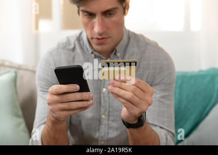 Young man at home using a smartphone Stock Photo