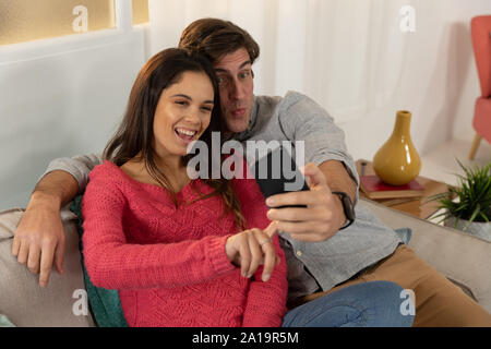 Young couple relaxing at home using a smartphone together Stock Photo