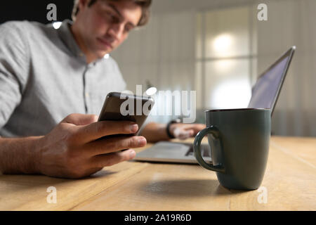 Young man using laptop computer and smartphone Stock Photo