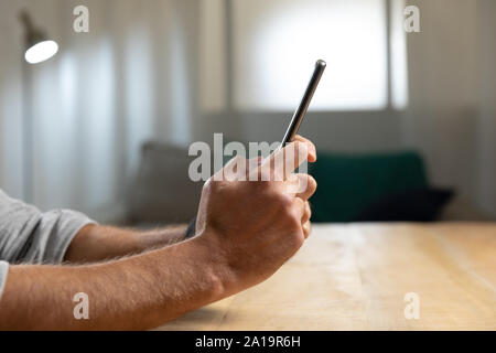 Young man at home using a smartphone Stock Photo