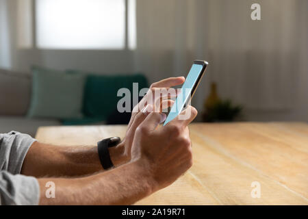 Young man at home using a smartphone Stock Photo