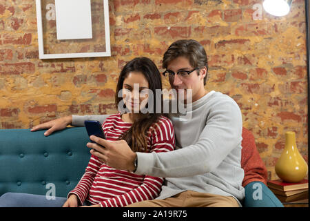 Young couple relaxing at home using a smartphone together Stock Photo