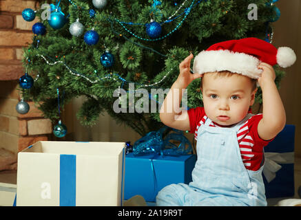 Cute little boy in santa hat near Christmas tree. xmas child Stock Photo