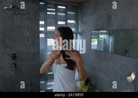 Young brunette woman brushing her hair in a modern bathroom Stock Photo