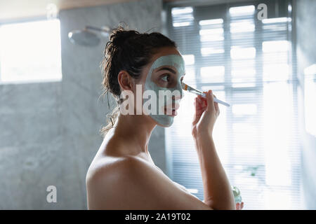 Young brunette woman applying face mask Stock Photo