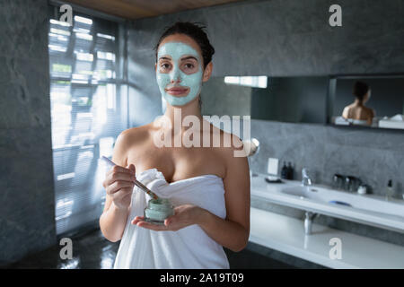 Portrait of young brunette woman applying face mask Stock Photo