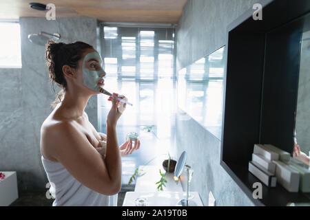 Young brunette woman applying face mask Stock Photo