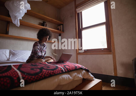 Young woman using laptop on her bed Stock Photo