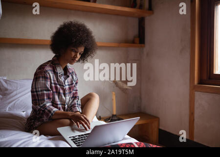 Young woman using laptop on her bed Stock Photo