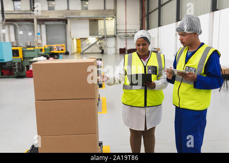 Factory workers talking in a factory warehouse Stock Photo