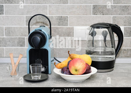 Coffee machine and electric kettle in the kitchen. Fresh fruits in white plate. Stock Photo