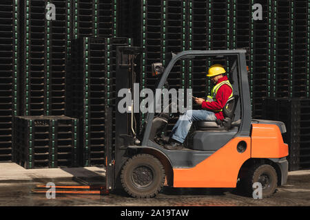 Factory worker driving a forklift truck outside a factory warehouse Stock Photo