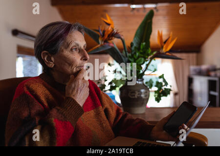 Senior woman holding tablet at home Stock Photo