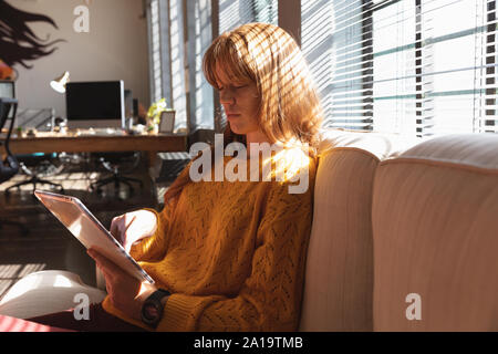 Young creative professional woman using tablet in a sunlit office Stock Photo