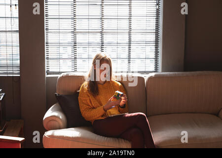 Young creative professional woman using smartphone in a sunlit office Stock Photo