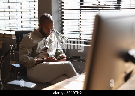 Young creative professional man using smartphone in a sunlit office Stock Photo