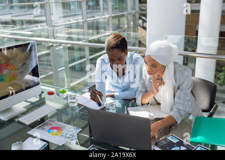 Females executives discussing over laptop at desk Stock Photo