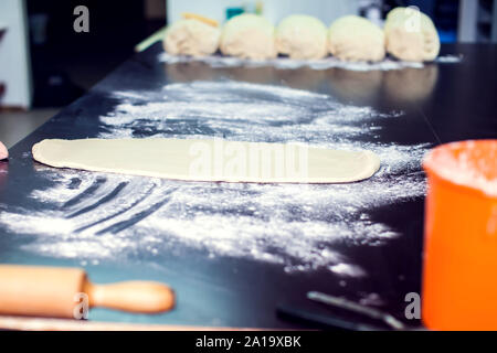 A chef rolls out the doughon on black table. Stock Photo