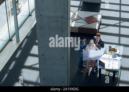 Male and female architects discussing over blueprint in office Stock Photo