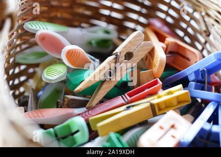 multi-colored wooden and plastic clothespins in a wicker basket. Stock Photo