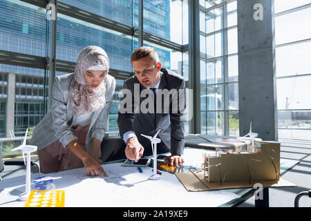 Male and female architects discussing over blueprint in office Stock Photo