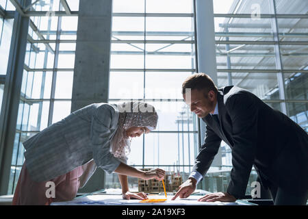 Male and female architects discussing over blueprint in office Stock Photo