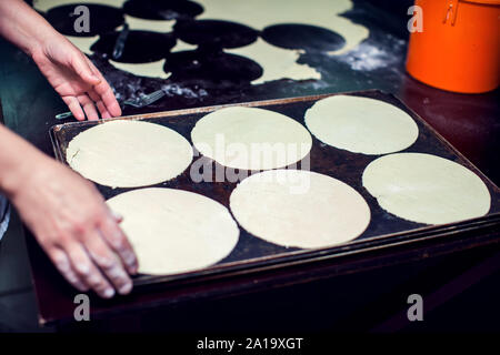 A chef rolls out the doughon on black table. Stock Photo