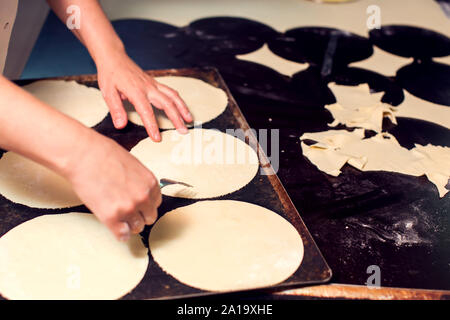 A chef rolls out the doughon on black table. Stock Photo