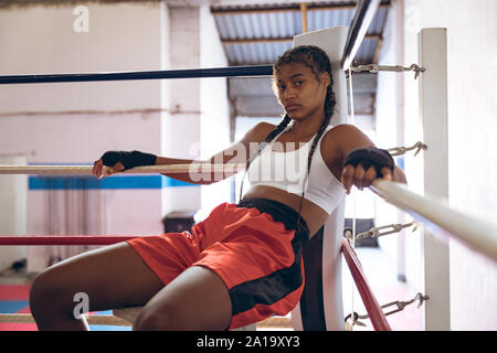 Female boxer relaxing in boxing ring at fitness center Stock Photo