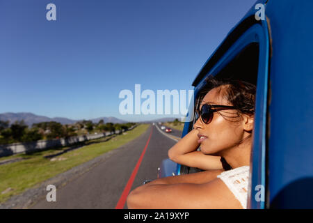 Young woman leaning out of the passenger window of a pick-up truck on the highway Stock Photo