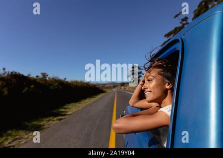 Young woman leaning out of the passenger window of a pick-up truck on the highway Stock Photo