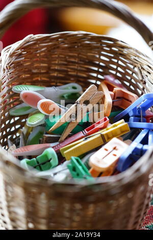 different wooden and plastic clothespins in a wicker basket Stock Photo