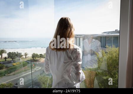 Young blonde woman looking out of window Stock Photo