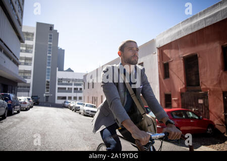 Young professional man riding a bike in a city Stock Photo