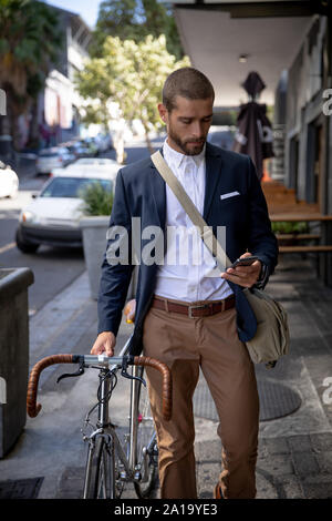 Young professional man using smartphone and holding a bike Stock Photo