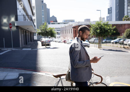 Young professional man using smartphone and holding a bike Stock Photo