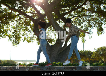 Two young women walking on a wall Stock Photo