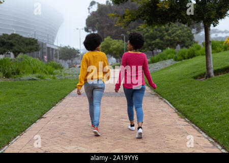 Two young women walking together in a park Stock Photo