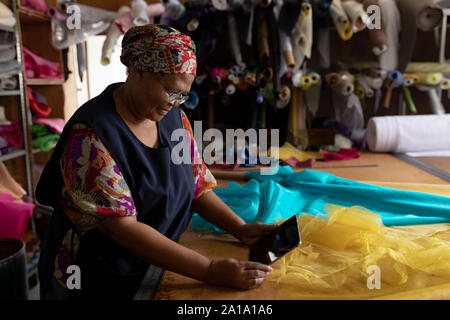 Middle aged woman using tablet at a hat factory Stock Photo