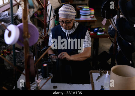 Woman using sewing machine in a hat factory Stock Photo