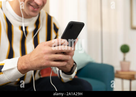 Young man at home using a smartphone Stock Photo