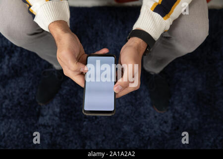 Young man at home using a smartphone Stock Photo