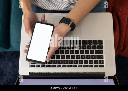 Woman using a smartphone and laptop Stock Photo